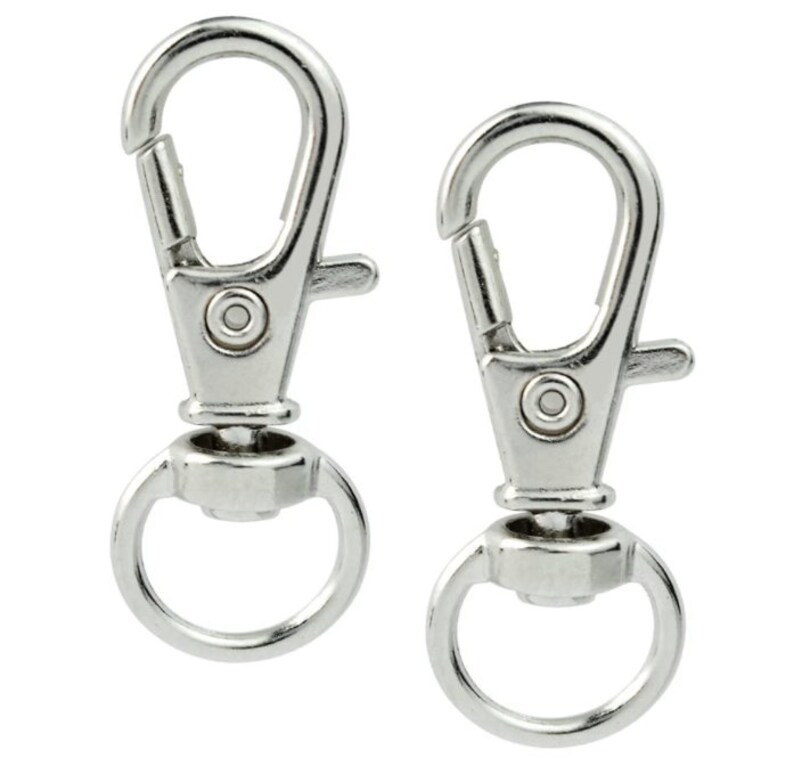 K&ouml;nnte beinhalten: Zwei silberne Drehkarabiner mit einem runden Ring am Boden. Die Karabiner sind geschlossen und bereit, an einer Leine, einem Schl&uuml;sselbund oder einem anderen Gegenstand befestigt zu werden.