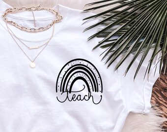 May include: White t-shirt with a black rainbow and the word "Teach" printed on the front. The shirt is paired with blue jeans and leopard print sandals.