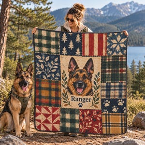 May include: A rectangular patchwork quilt featuring a central portrait of a German Shepherd dog with the name Ranger printed below it. The quilt is composed of various squares with patterns including green plaid, red stripes, pine trees, and paw prints.