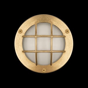 Pode incluir: Uma luminária de parede redonda, cor de latão, para exterior. A luminária tem uma moldura circular com uma grelha sobre um globo de vidro fosco. Três parafusos prendem a moldura. Projetada para uso externo.