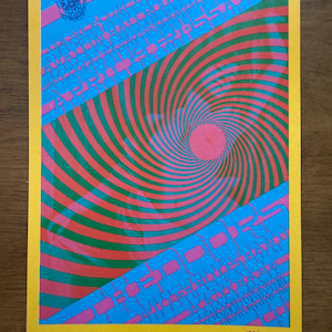May include: A psychedelic poster with a yellow border features a spiral design in red and green, set against a blue background. Pink geometric shapes and text are also present. The poster has a vintage aesthetic.