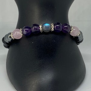 May include: A beaded bracelet with black, pink, purple, and blue stones. The bracelet has silver accents.