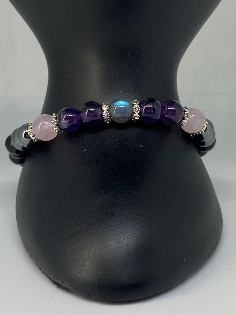 May include: A beaded bracelet with black, pink, purple, and blue stones. The bracelet has silver accents.