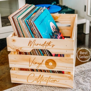May include: A wooden crate with the words "Meredith's Vinyl Collection" engraved on the front. The crate is filled with vinyl records.