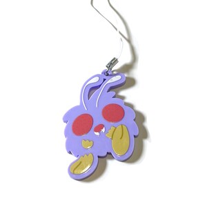 Peut inclure: Un charm en forme de lapin violet avec des joues rouges et des détails dorés sur les oreilles et les pattes. Le charm a une ficelle blanche pour l'accrocher. Un accessoire mignon.