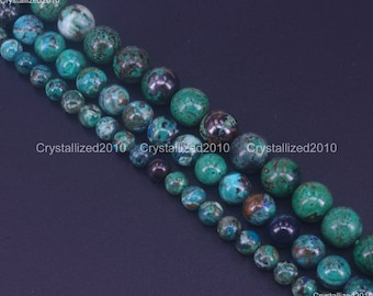 May include: Strands of round, polished beads in varying sizes. The beads display a mix of teal, turquoise, and dark green hues with speckled patterns. The beads are arranged in parallel rows against a dark background. The text "Crystallized2010" is visible.