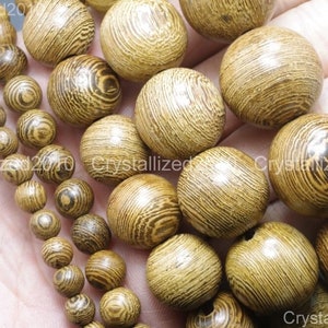 May include: A collection of round wooden beads with a natural wood grain pattern. The beads are various sizes and are a light brown color.