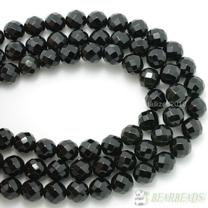 May include: A strand of black faceted gemstone beads. The beads are round and have a polished finish.