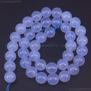 May include: A strand of light blue round gemstone beads. The beads are smooth and translucent, with a slight shimmer. The beads are strung on a blue thread.