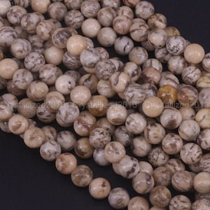 Puede incluir: Una hebra de cuentas redondas de piedra preciosa, de color beige y marrón con patrones. Las cuentas tienen un acabado liso y pulido.