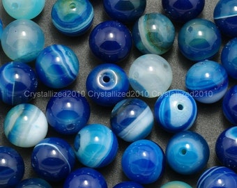 May include: A collection of blue and white agate beads. The beads are round and have a smooth, polished finish. They are perfect for making jewelry or other crafts.