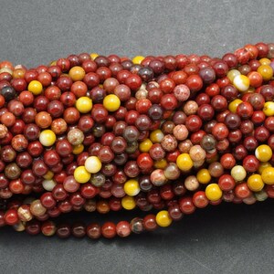 May include: A strand of red, yellow, and brown gemstone beads. The beads are round and have a smooth, polished finish.
