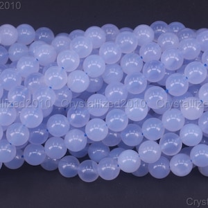 May include: A close-up of a strand of light blue round gemstone beads. The beads are smooth and polished, and they have a translucent appearance.