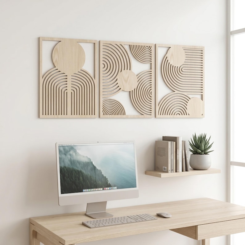May include: A set of three rectangular light-colored wooden wall panels featuring intricate laser-cut geometric patterns of concentric circles and arches. The panels are arranged horizontally on a white wall above a computer desk and a small shelf.