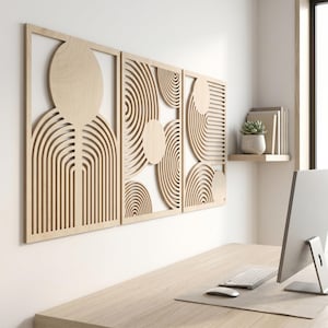 May include: A set of three rectangular light-colored wooden wall panels featuring intricate laser-cut designs. Each panel displays a series of concentric circular patterns and arching lines, creating a geometric composition of negative space.
