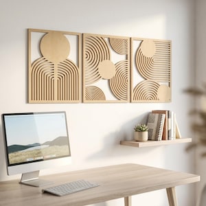 May include: A set of three rectangular light-colored wooden wall panels featuring laser-cut geometric patterns of concentric circles and arching lines. The panels are arranged horizontally on a wall above a desk with a computer monitor and keyboard.