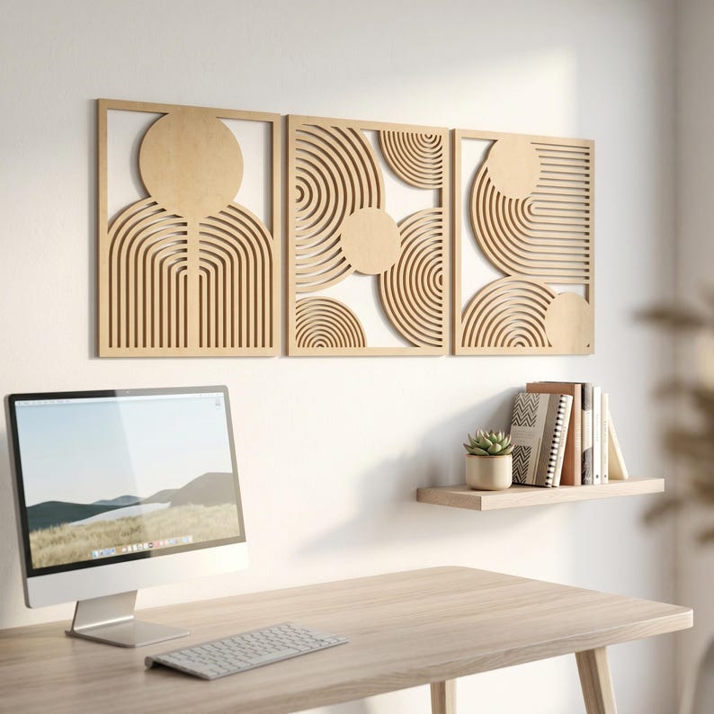 May include: A set of three rectangular light-colored wooden wall panels featuring laser-cut geometric patterns of concentric circles and arching lines. The panels are arranged horizontally on a wall above a desk with a computer monitor and keyboard.