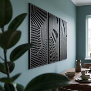 May include: A set of three rectangular wall panels featuring a black geometric pattern of parallel lines arranged in varying directions. The panels are mounted side-by-side on a wall, creating a cohesive visual display of intersecting linear shapes.