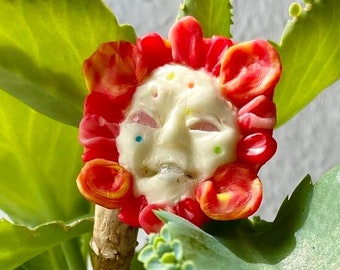Blumen-Brosche mit Lächeln, roten Blütenblättern und fluoreszierendem Gesicht