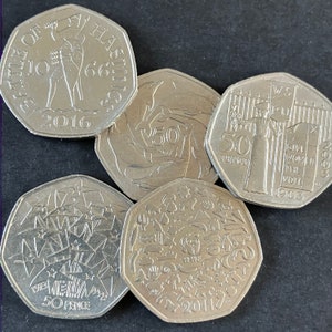 May include: Five silver 50 pence coins from the United Kingdom. The coins feature different designs, including the Battle of Hastings, dolphins, a woman with a banner that reads "Give Women the Vote 1903", and a design with a variety of symbols.