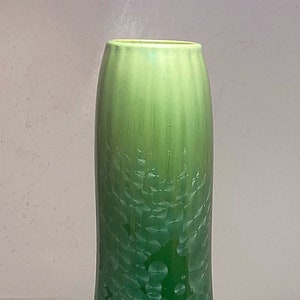 May include: A green glass vase with a pear-shaped body and a textured, bubbly surface. The vase has a light green color at the top that gradually transitions to a darker green at the bottom.