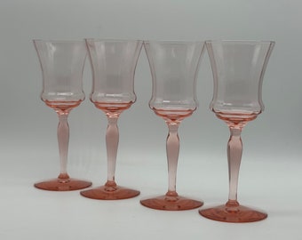 May include: Set of four pink glass wine glasses with a delicate design. The glasses have a clear base and a pink tinted bowl.