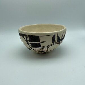 May include: A white ceramic bowl with black and brown geometric designs. The bowl is hand-painted and has a traditional Southwestern style.