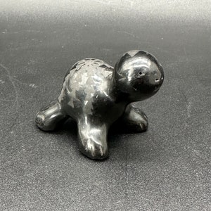 May include: Black ceramic turtle figurine with a textured shell and a small hole on the head.