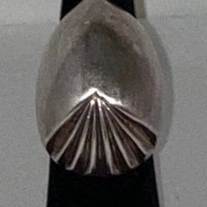 May include: A silver ring with a geometric design. The ring is oval shaped and has a textured surface.
