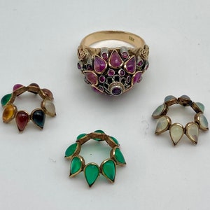 May include: A gold ring with a cluster of pink, red, and green gemstones. There are three smaller rings with gemstones in different colors.