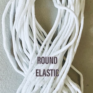 May include: A close-up of a white round elastic cord. The cord is coiled and arranged in a figure eight shape. The text "ROUND ELASTIC" is printed in black on the cord. The text "FAST SHIPPING!" is printed in green and yellow at the top of the image. The text "USA SELLER" is printed in blue at the bottom of the image.