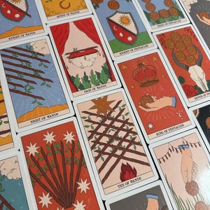 K&ouml;nnte beinhalten: Eine Sammlung von Tarotkarten mit verschiedenen Illustrationen, darunter Acht der St&auml;be, Page der St&auml;be, Ritter der M&uuml;nzen, Sieben der M&uuml;nzen, K&ouml;nig der M&uuml;nzen und Zehn der St&auml;be. Jede Karte zeigt deutliche Motive wie St&auml;be, M&uuml;nzen, Schilde und Kronen in einem farbenfrohen, grafischen Stil mit klaren Textbeschriftungen.