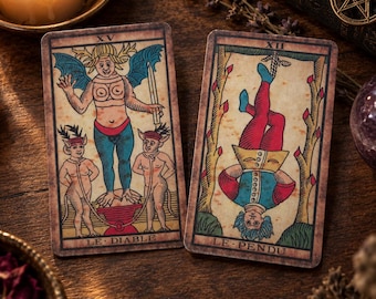Puede incluir: Dos cartas de tarot rectangulares con ilustraciones de estilo vintage. La carta de la izquierda, etiquetada LE DIABLE, muestra una figura alada con dos personajes más pequeños. La carta de la derecha, LE PENDU, muestra una figura colgada.