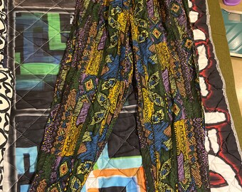 May include: A pair of black pants with a colorful geometric pattern. The pattern features shades of yellow, blue, green, and purple. The pants have a wide leg and a high waist.