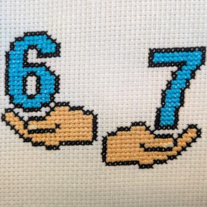 Könnte beinhalten: Kreuzstich-Stickerei der Zahlen 6 und 7 in Hellblau, jeweils gehalten von einer hellbraunen Hand. Die Zahlen und Hände sind schwarz auf weißem Stoffgrund umrandet. Der Stil erinnert an Pixelkunst.