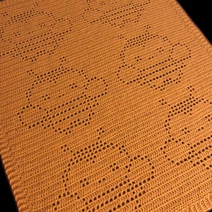 May include: A crocheted blanket in a warm orange color with a repeating pattern of circles.