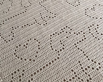 Könnte beinhalten: Nahaufnahme einer beige gehäkelten Decke mit einem Rautenmuster.