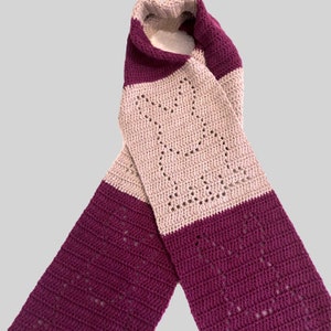 May include: A crocheted scarf with alternating stripes of purple and beige. The scarf has a lacy pattern.