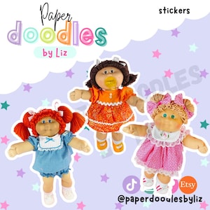 May include: Three Cabbage Patch Kids dolls are featured in this image. One doll has red pigtails and a blue dress, another has brown hair and an orange dress, and the third has blonde pigtails and a pink dress. The words "Paper Doodles by Liz" and "stickers" are also visible.