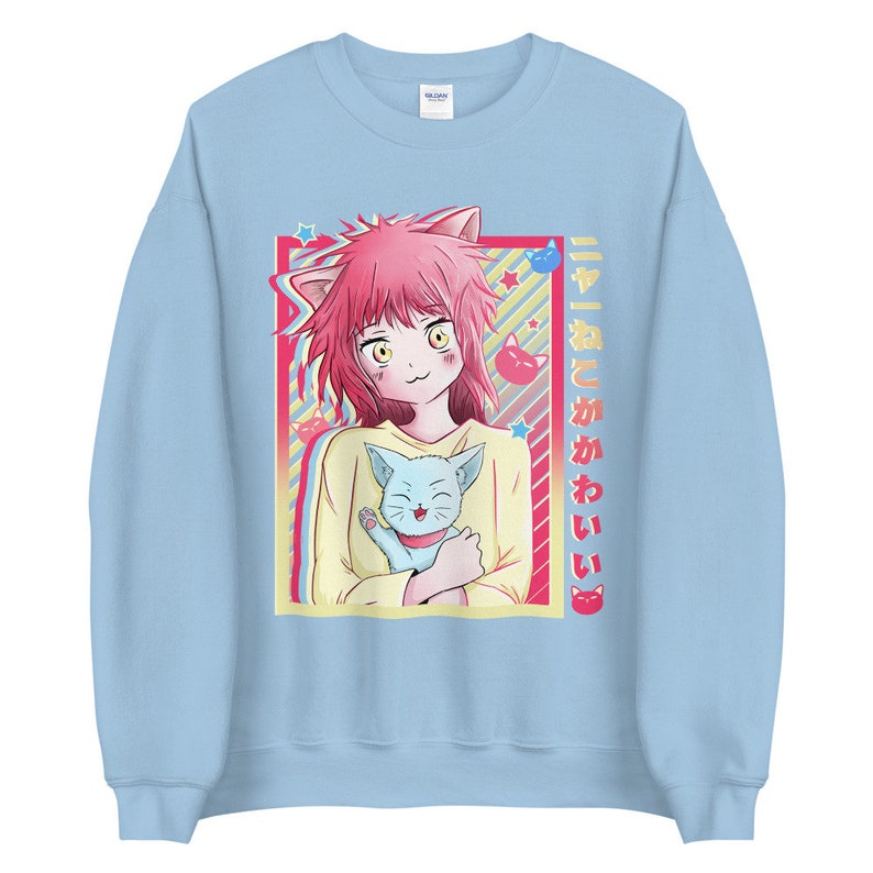 May include: A light blue sweatshirt with a graphic of a pink-haired anime girl holding a blue cat. The graphic is surrounded by a yellow and pink frame with stars and the text "ネコと かわいい" in Japanese.