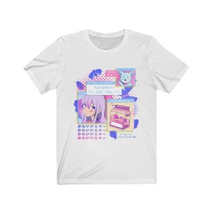 Pu&ograve; includere: Una maglietta bianca con un design grafico colorato che presenta una ragazza dei cartoni animati con i capelli rosa, un gatto e un cartone di succo. Il testo sulla maglietta recita "NEOH", "Hexo ga daisuki", "chou kawaii", "kawaii" e "kawaii Nya".