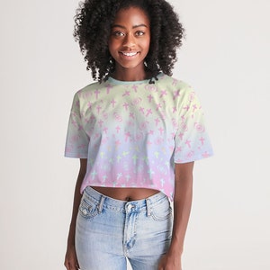 May include: A cropped t-shirt with a pastel pink, blue and yellow ombre design. The shirt features a repeating pattern of pink crosses and white swirls.