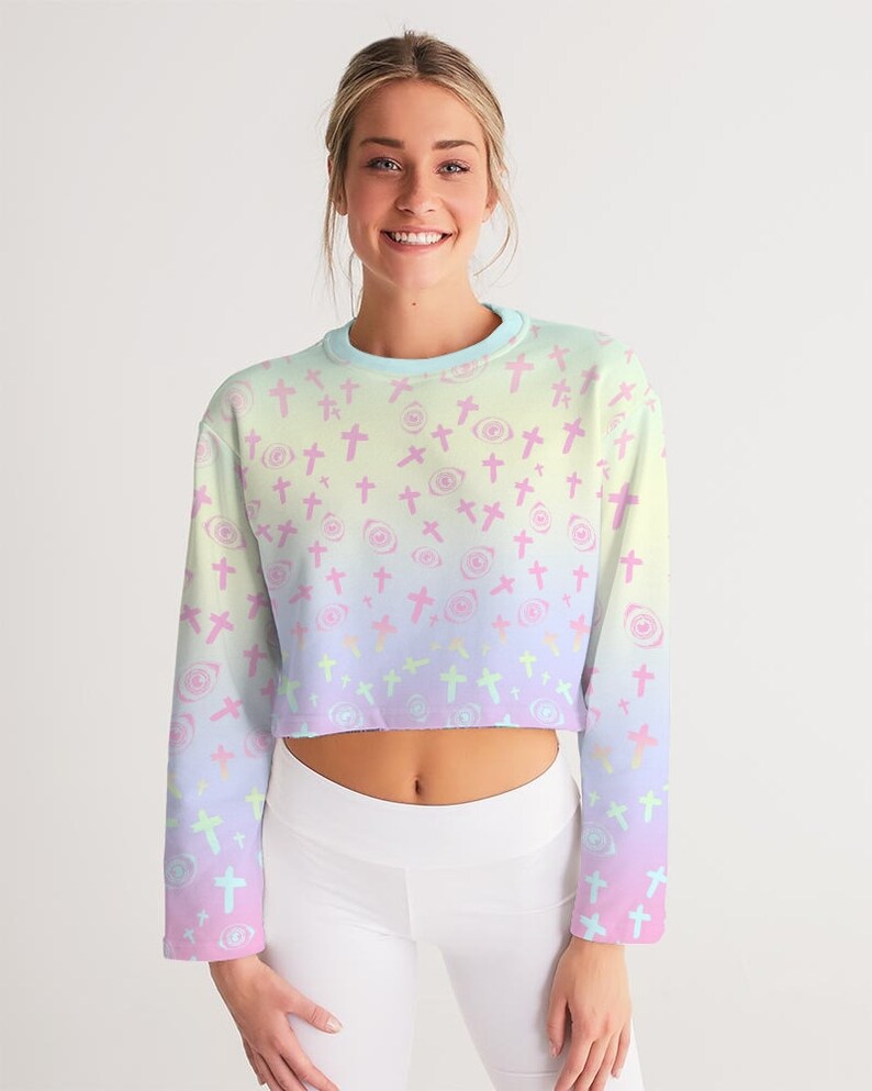 May include: A pastel rainbow ombre cropped sweatshirt with a pattern of pink crosses and swirls. The sweatshirt has long sleeves and a crew neck.