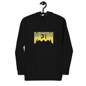 Pu&ograve; includere: Felpa con cappuccio nera con una grafica "MEOW" in oro e giallo in uno stile di font da videogioco retr&ograve;.