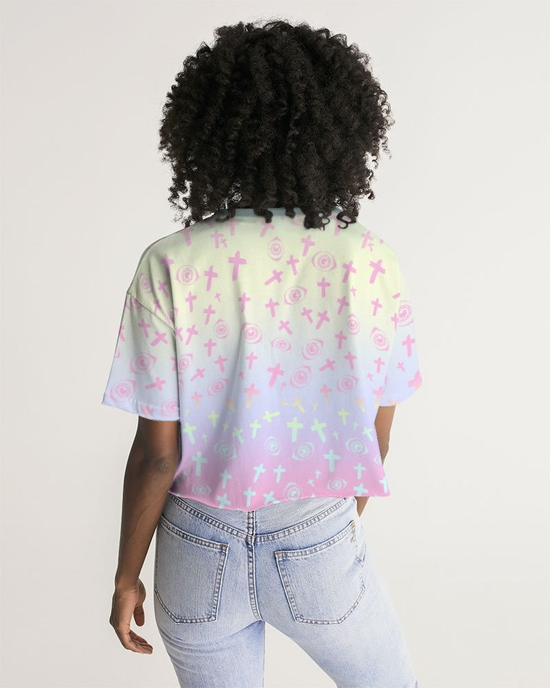 May include: A pastel pink, yellow and blue ombre cropped t-shirt with a pattern of pink crosses and white eyes.