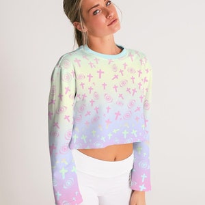 May include: A pastel rainbow ombre cropped long-sleeved sweatshirt with a repeating pattern of pink crosses and eyes.