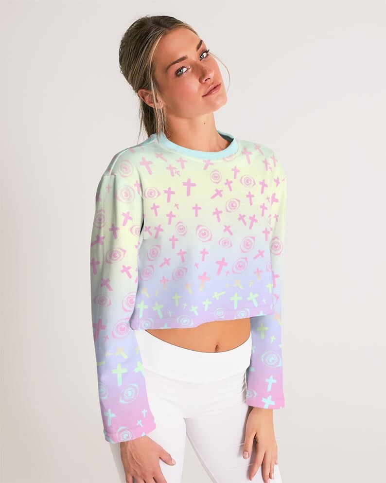 May include: A pastel rainbow ombre cropped long-sleeved sweatshirt with a repeating pattern of pink crosses and eyes.
