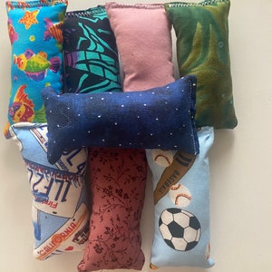 May include: A collection of nine colorful fabric pillows with various patterns and designs. The pillows are made of soft, plush fabric and are perfect for adding a touch of personality to any room.
