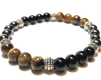 May include: A beaded bracelet with black, brown, and gold beads separated by silver spacers. The bracelet is made with tiger's eye, hematite, and onyx stones.