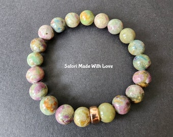 May include: A green, pink, and brown gemstone bracelet with a gold accent bead. The bracelet is made of round beads and has a total of 18 beads. The text "Satori Made With Love" is visible in the image.